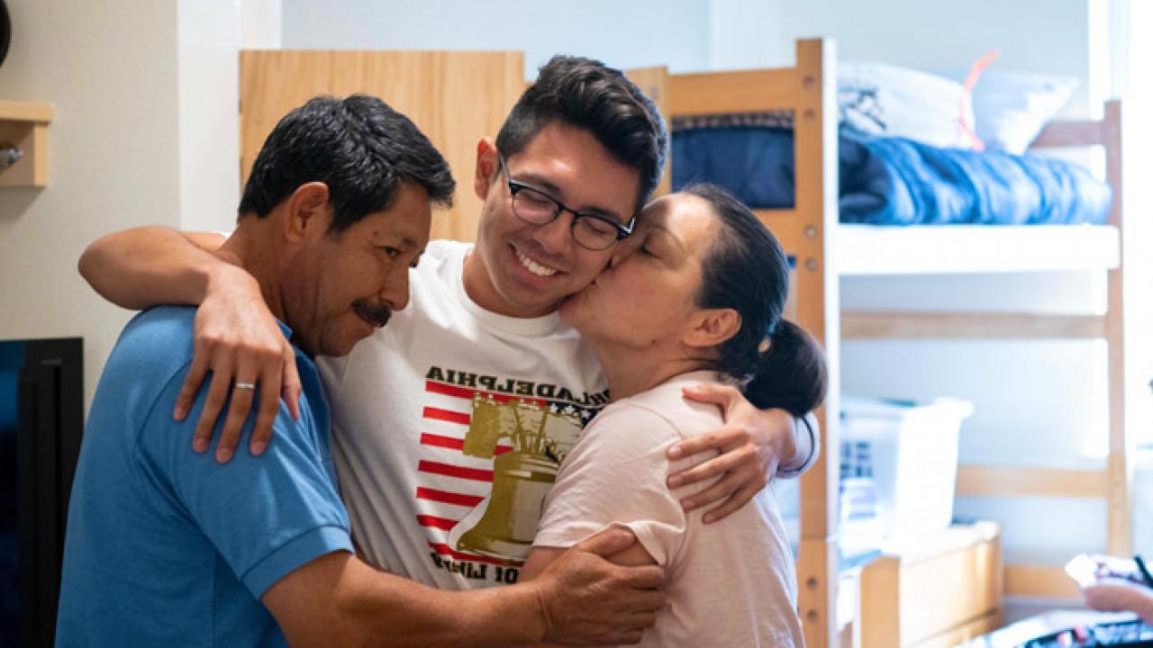 一个学生在宿舍里拥抱他的父母